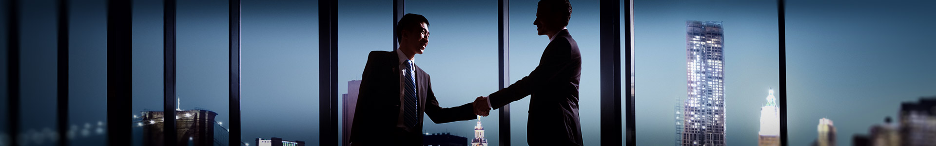 two businessmen shaking hands together at a desk in a office in business skyscraper